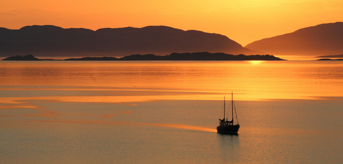 Fishing boat on golden sunset water with mountains, Aliyah Marine hero